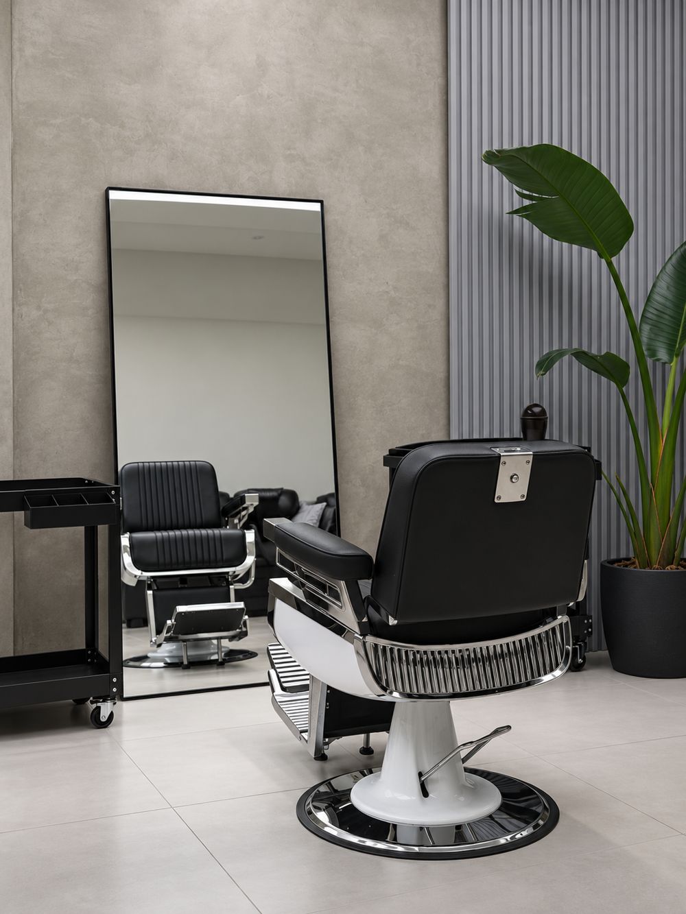 Sillón de barbero junto a un espejo de pie y una planta
